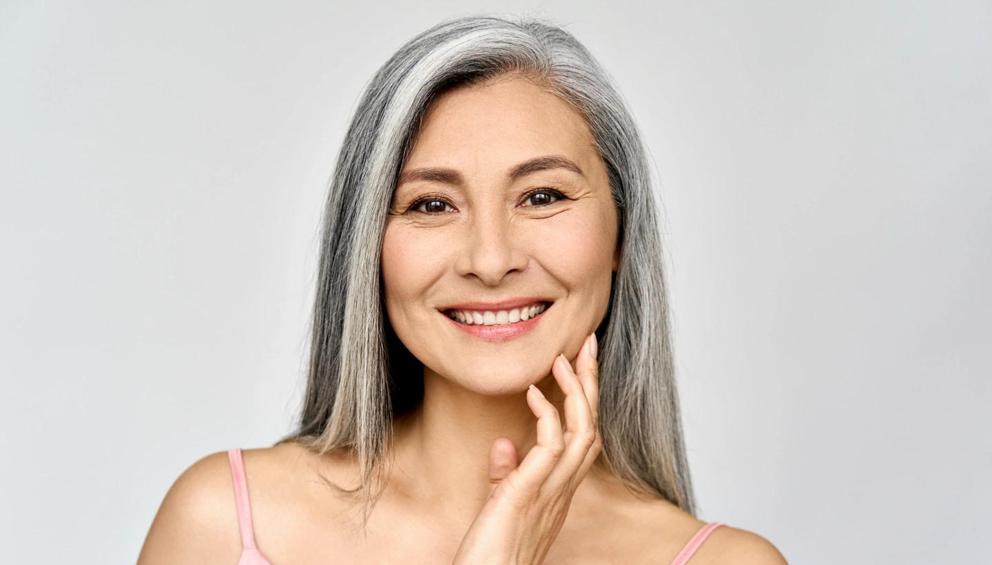mature grey haired woman touching her face